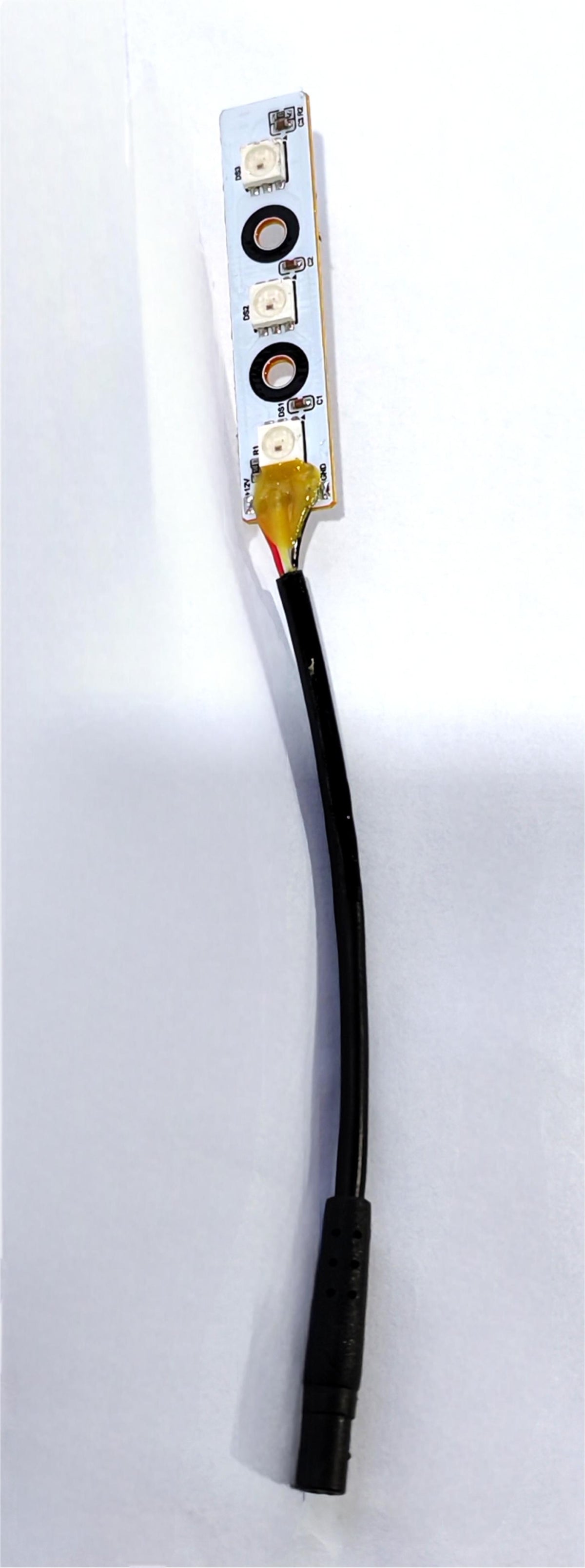 Module LED de bras arrière gauche avec son câble de connexion noir posé sur un fond blanc