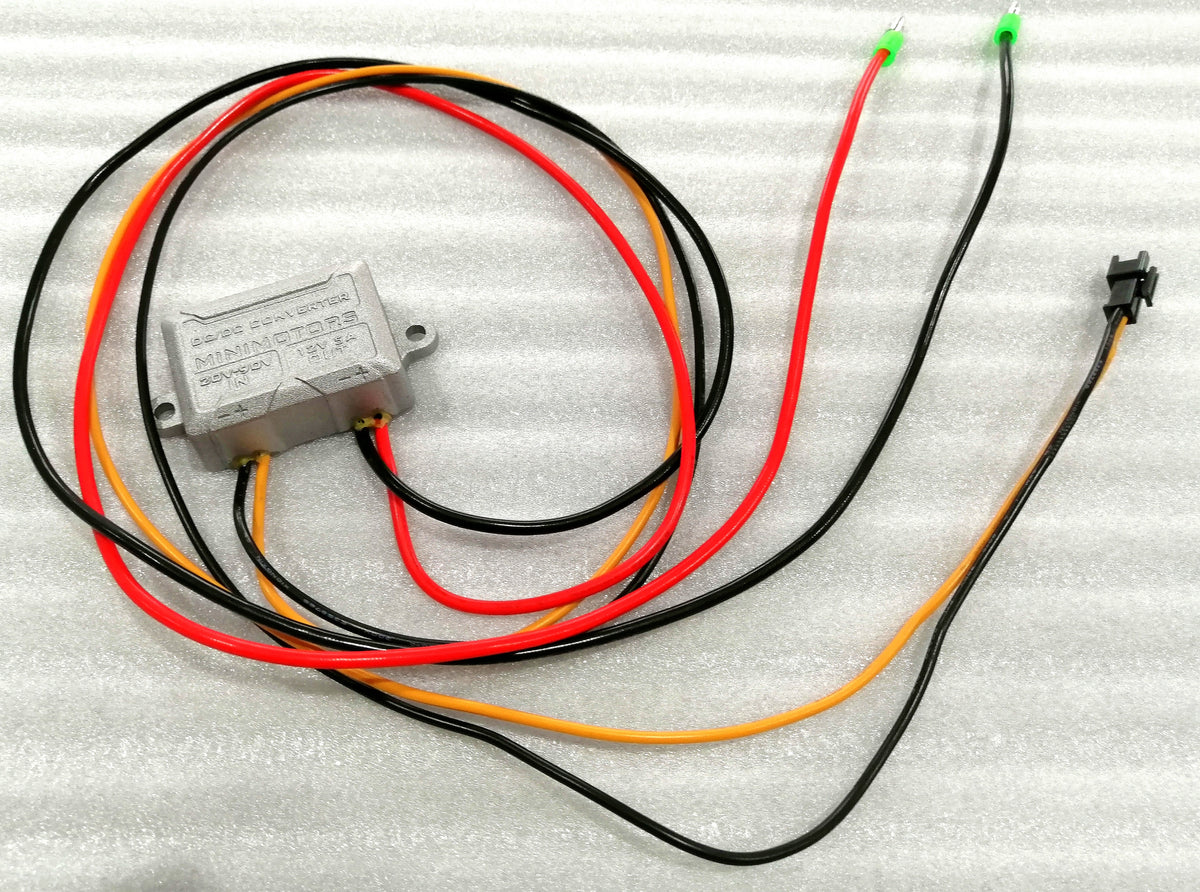 Boîtier convertisseur DC-DC Minimotors avec ses câbles électriques posé à plat sur fond blanc.