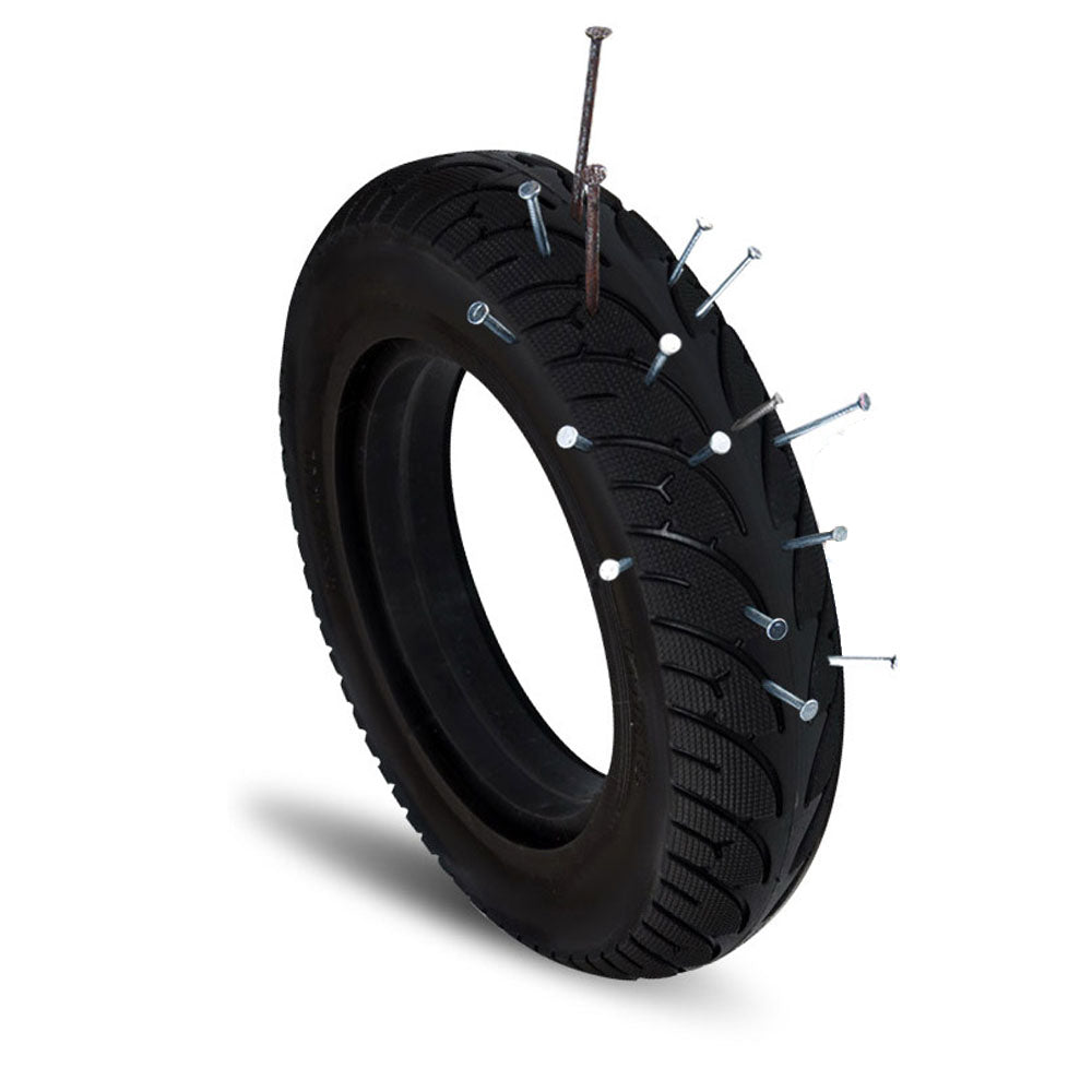 Pneu plein noir 10 pouces pour trottinette électrique transpercé de clous illustrant sa résistance aux crevaisons