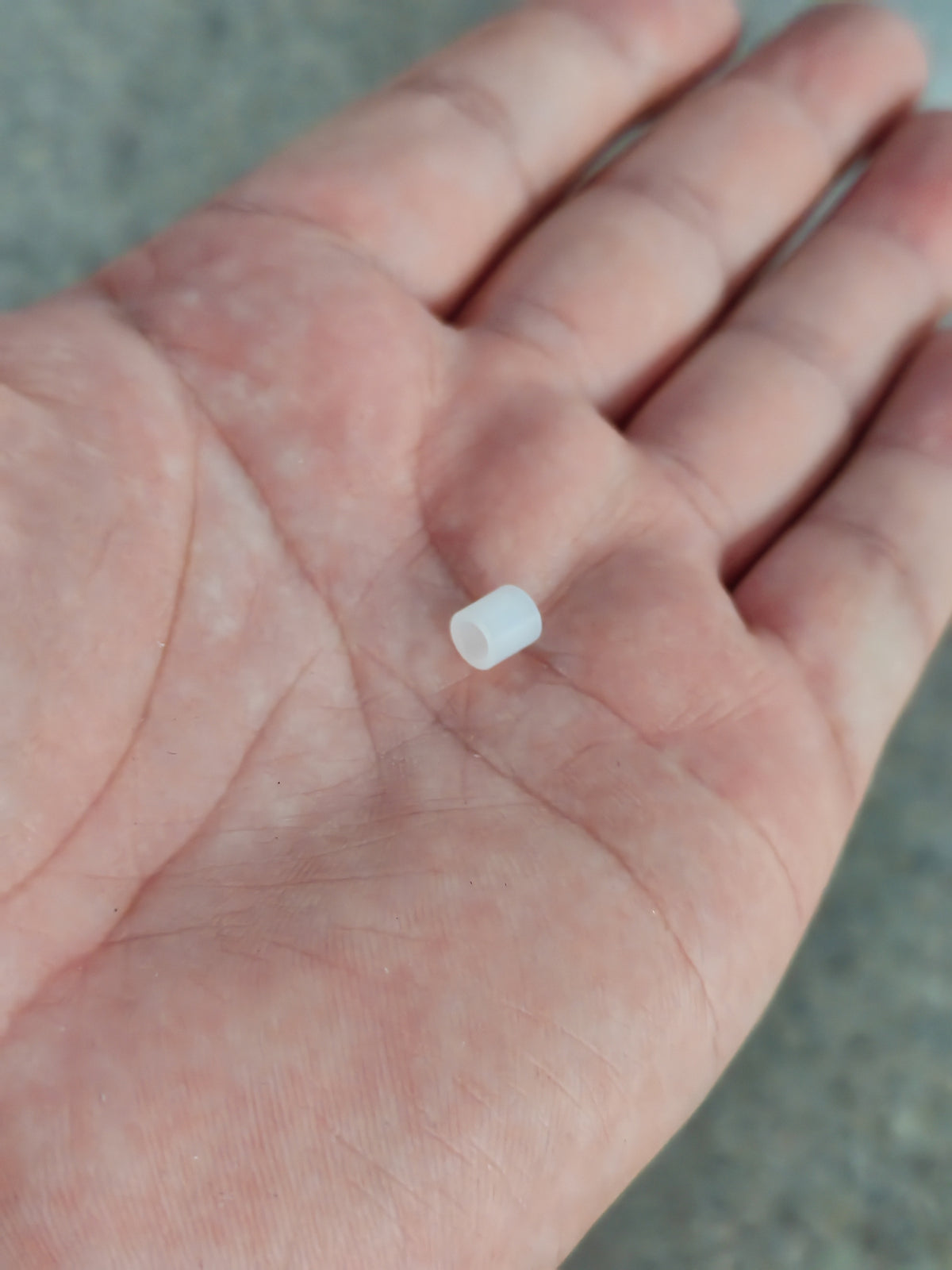 Petite bague plastique blanche pour trottinette Dualtron Sonic Alien posée dans la paume d'une main