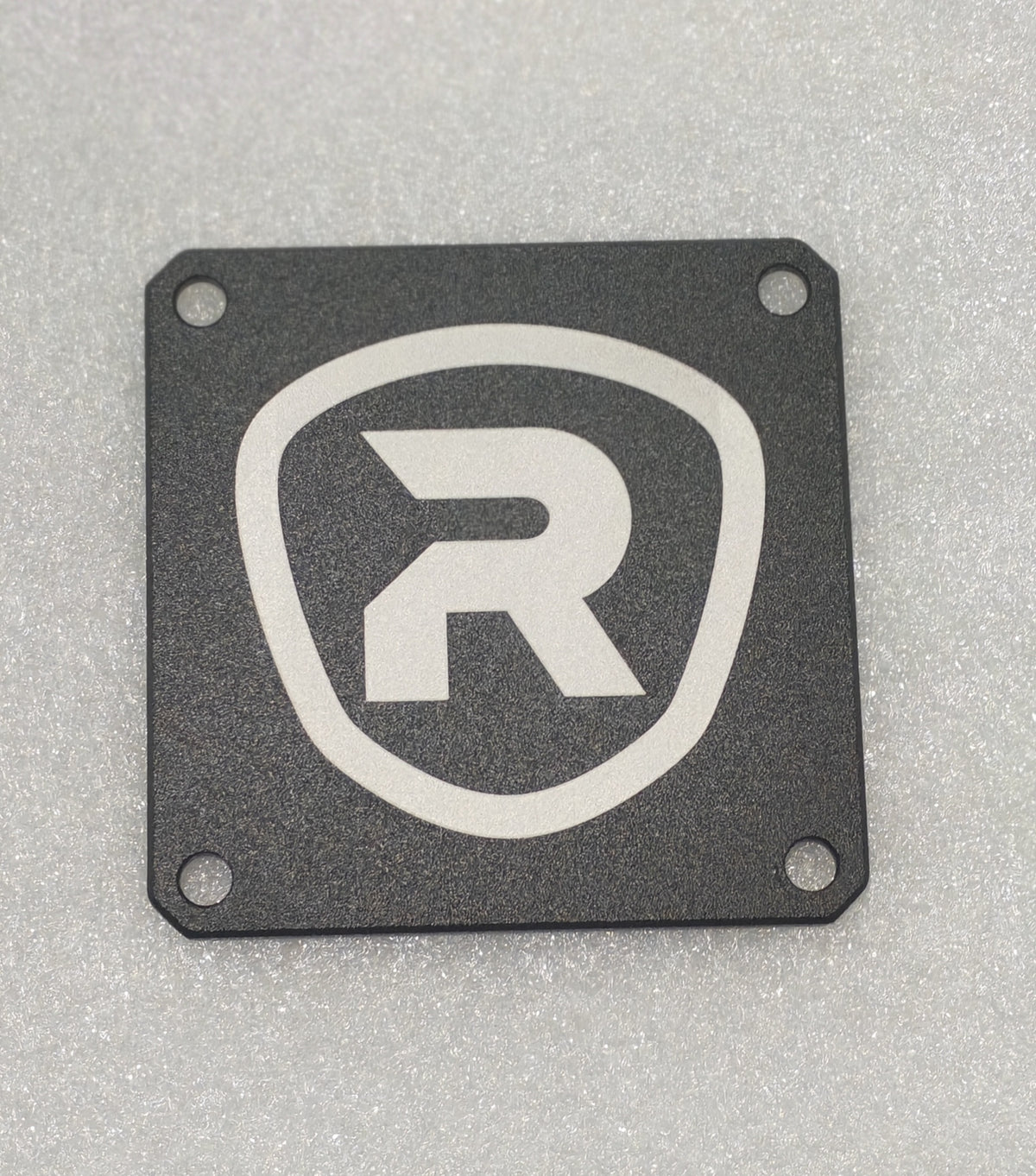 Plaque de base de selle noire carrée avec le logo Rovoron blanc au centre et quatre trous de fixation
