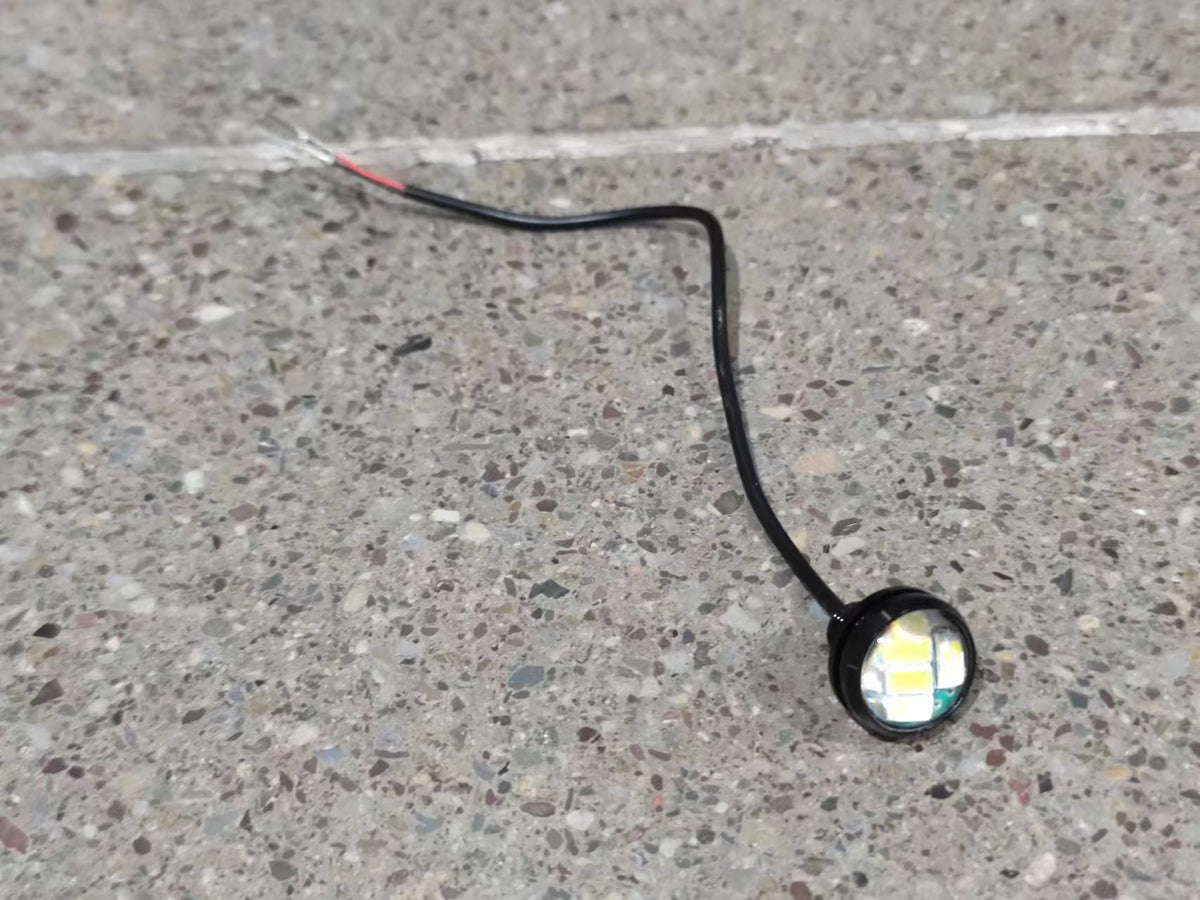 Feu LED avant blanc de trottinette électrique Dualtron relié à un câble noir sur un sol en pierre