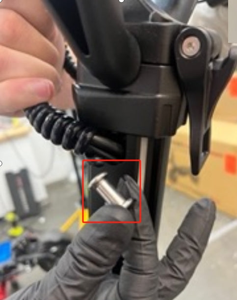 Vis métallique du système de pliage tenue à la main devant la potence d'une trottinette électrique Dualtron