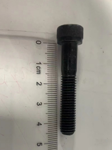 Vis noire 8x45 de capuchon de suspension posée à côté d'une règle graduée