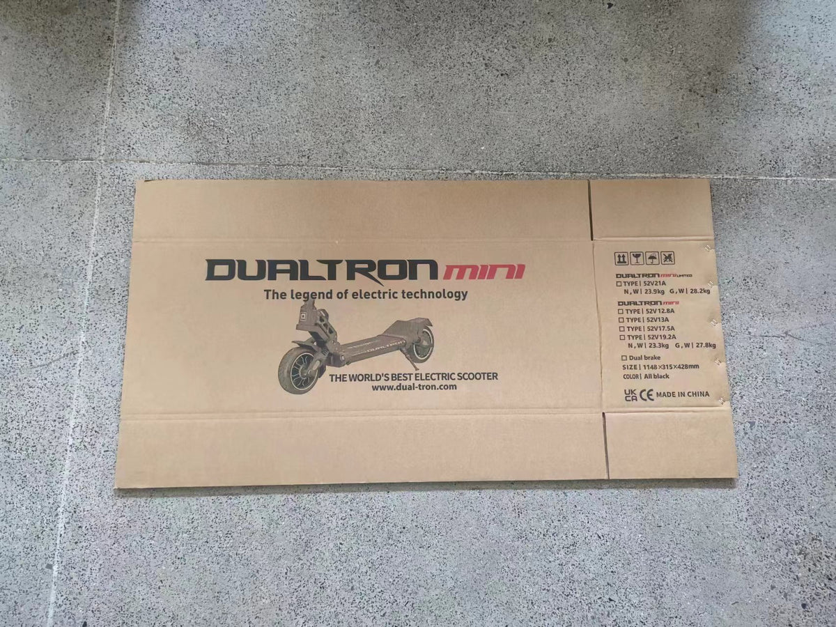 Carton d'emballage externe aplati imprimé du logo Dualtron Mini posé sur le sol