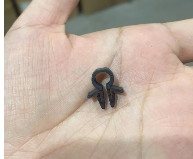 Clip de fixation de câble noir en plastique tenu dans le creux d'une main