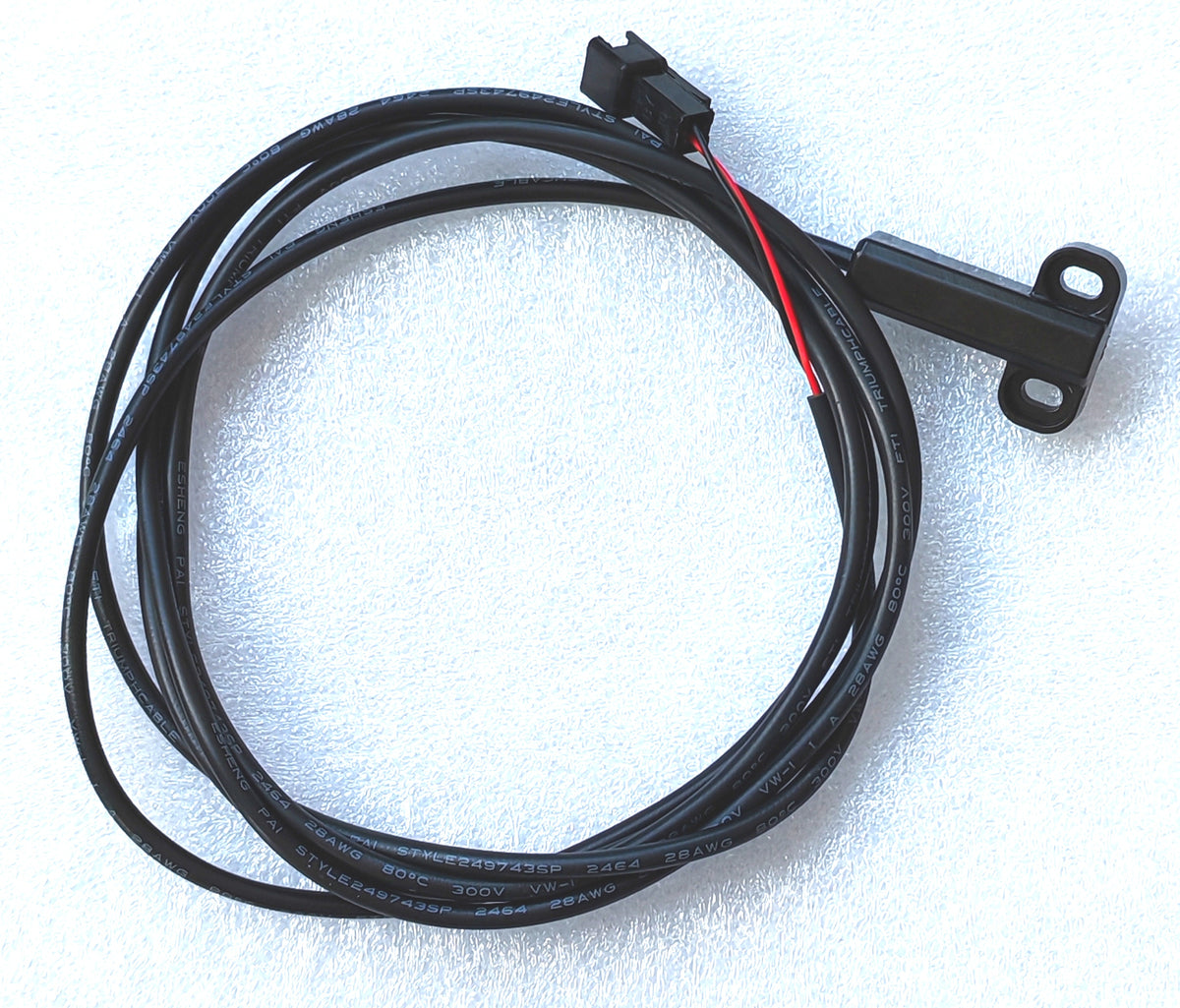 Capteur de frein hydraulique noir avec son câble enroulé sur fond blanc