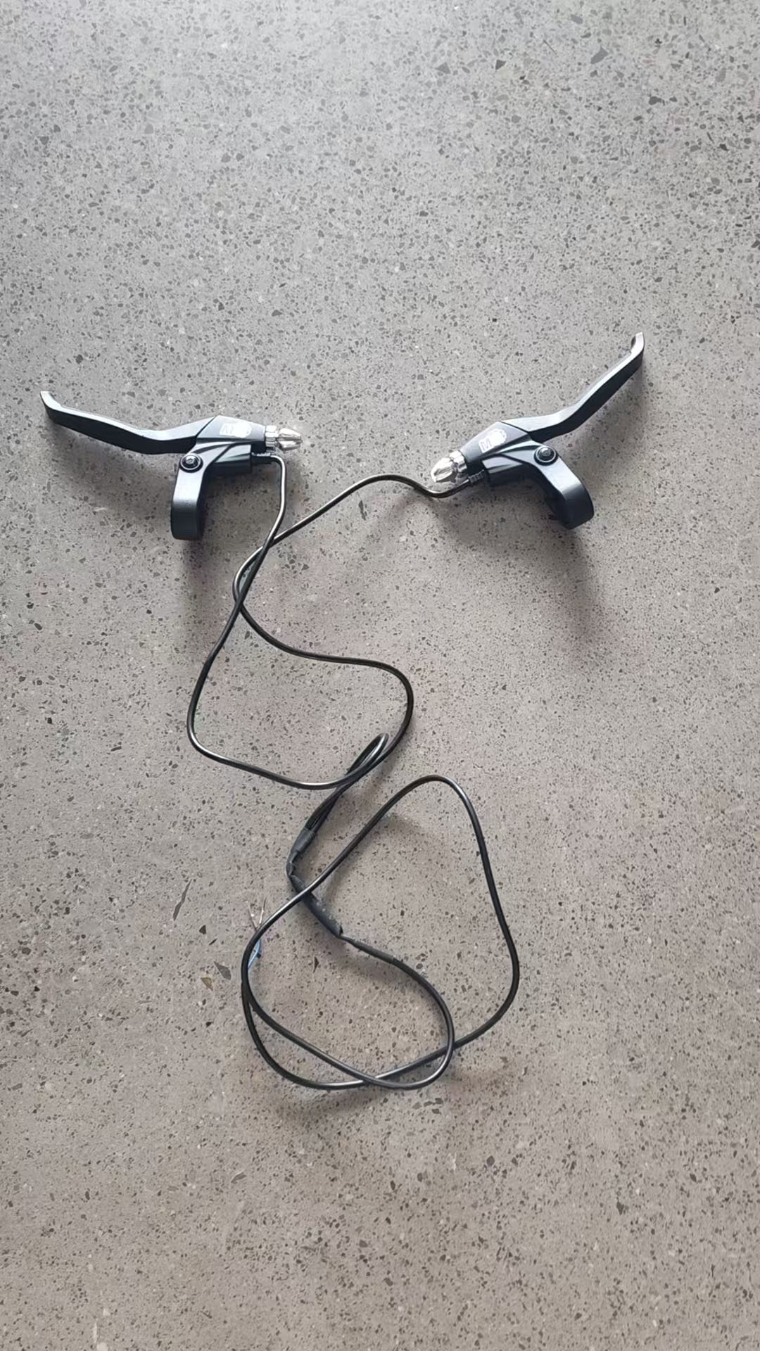 Poignées de frein gauche et droite noires avec leurs câbles pour Dualtron Ultra posées sur le sol