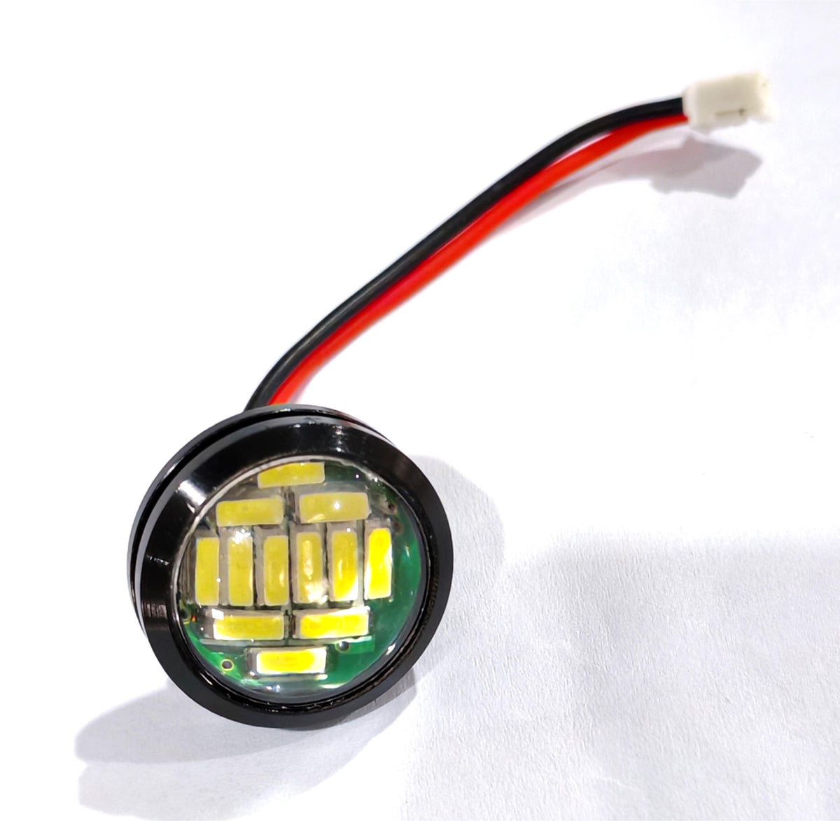Module d'éclairage LED rond encastré avec son câble d'alimentation rouge et noir.