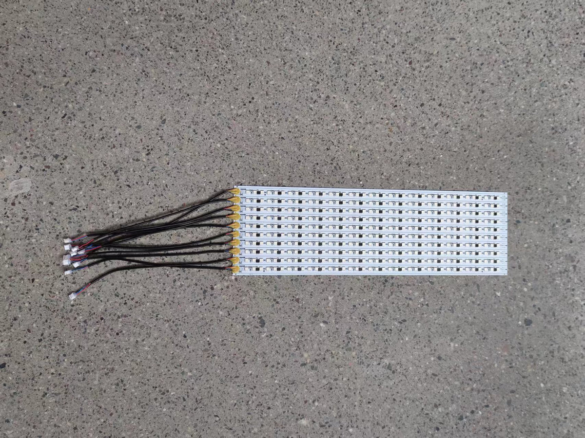 Carte LED de châssis droit avec ses câbles de connexion posée à plat sur un sol en béton