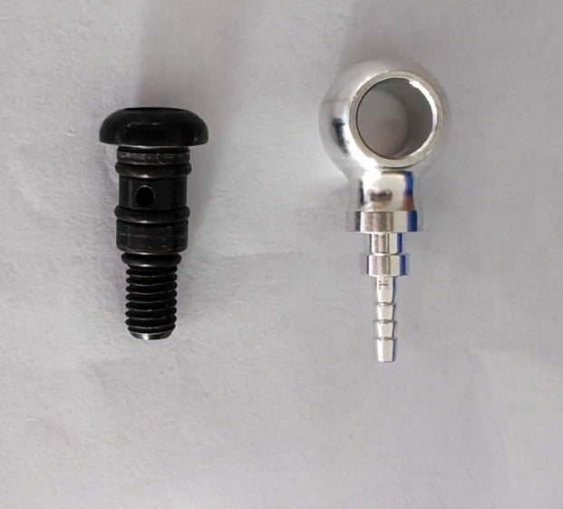 Raccord hydraulique argenté et vis de banjo noire posés côte à côte sur un fond blanc
